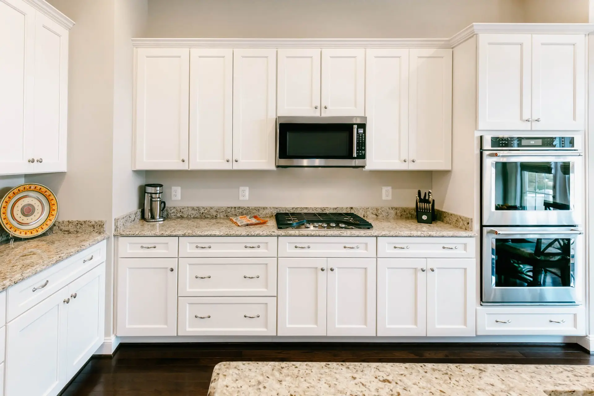 White painted shaker kitchen cabinets with granite counters and stainless double wall ovens