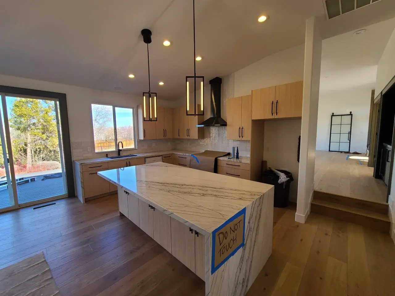 Newly painted open-plan kitchen with white walls, light wood cabinets and a marble waterfall island